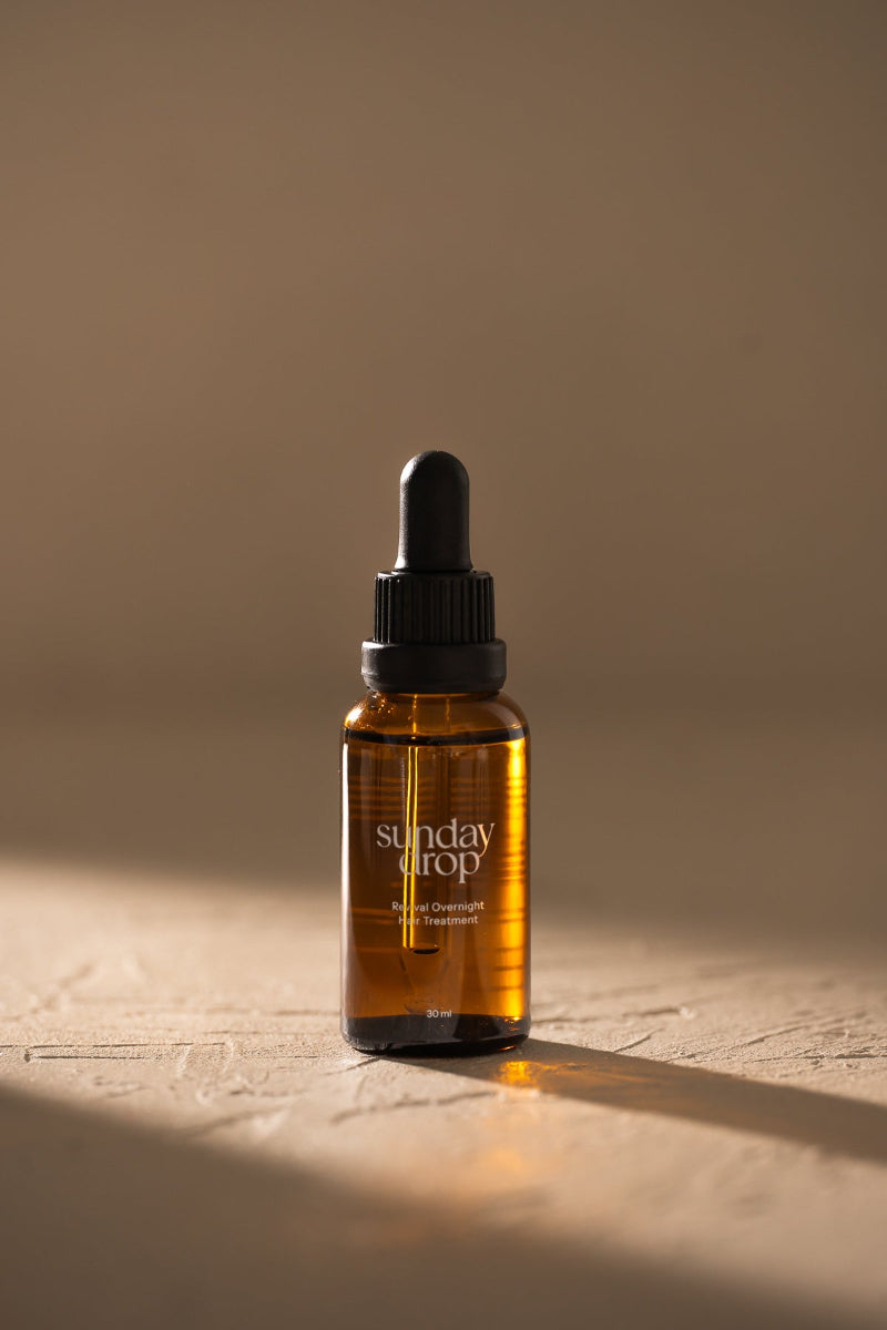 Brown glass dropper bottle labeled 'sunday drop' on a beige background